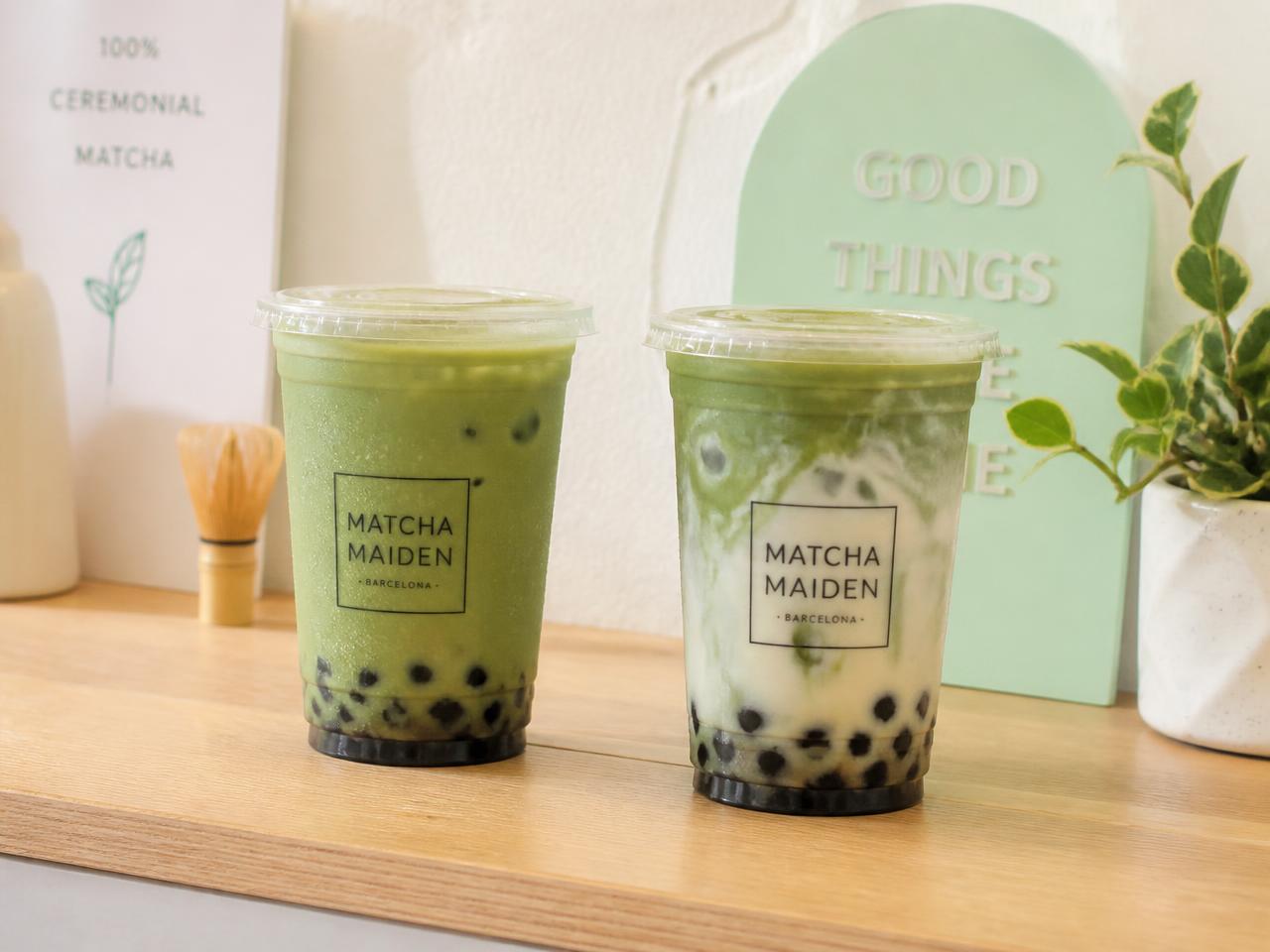 Dos bubble teas de matcha con perlas de tapioca sobre un mostrador de madera